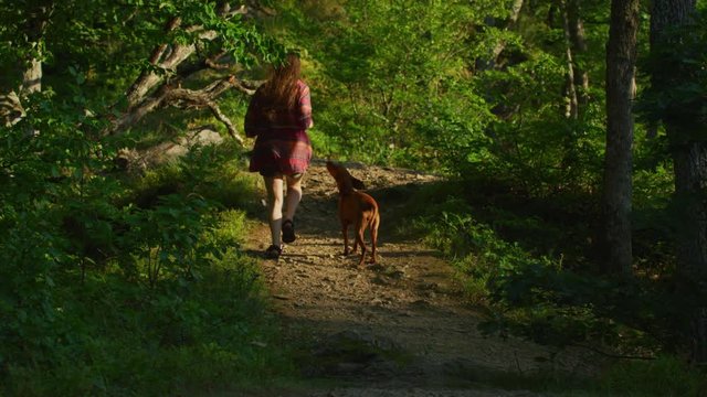 Woman running with her dog on a forest path