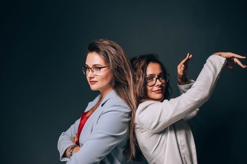 Business team of two young, successful and beautiful women. Long-haired girls in business clothes.