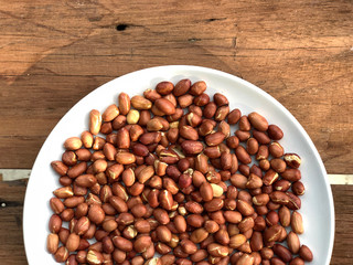 peeled peanuts in white dish on wooden table with natural light , ingredients of peanut butter. Healthy food.top view and copy space.