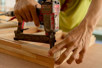 wood work carpenter concept with close up hand use nail gun machine