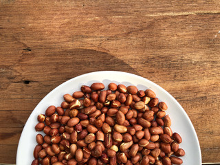 peeled peanuts in white dish on wooden table with natural light , ingredients of peanut butter. Healthy food.top view and copy space.