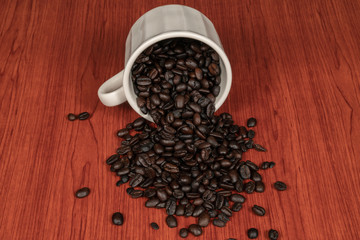 Coffee beans in white cup with wooden background