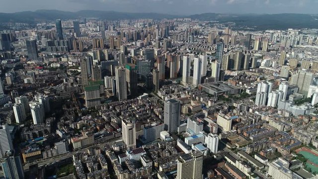 Aerial drone shot flying towards residential apartment buildings and skyline of Kunming city in China