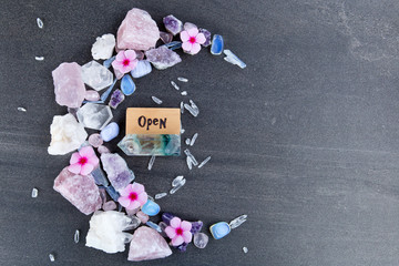 Open sign for alternative therapy business - word burnt in wood with crystals and flowers in...