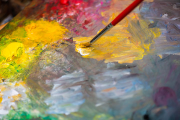 Obraz premium Paint brush on a paint palette with multicolor oil paint