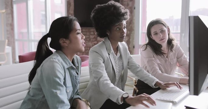 Female coworkers looking at a desktop computer together