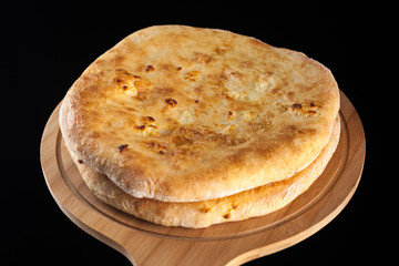 Georgian traditional food khachapuri on the wooden dish on black background