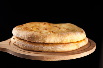 Georgian traditional food khachapuri on the wooden dish on black background
