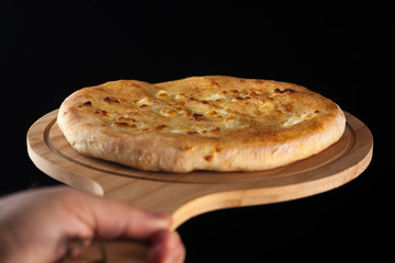 Georgian traditional food khachapuri on the wooden dish on black background