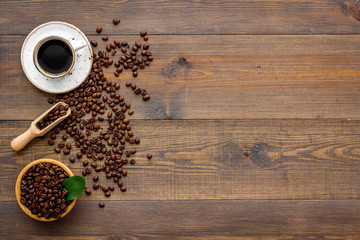 Obraz na płótnie Canvas Brown roasted coffee beans scattered on wooden background and cup of americano top view mockup