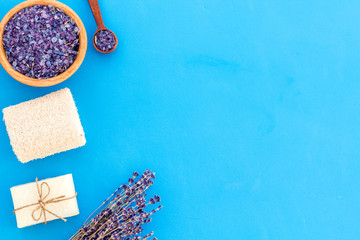 Spa set with lavender spa salt. Purple spa salt near dry lavender branches and washcloth on blue background top view space for text