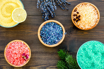 Aromas of bath salt. Lemon, coffee, rosemary, rose, lavender near bowls with colorful bath salt on dark wooden background top view
