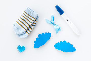 Pregnancy and preparation for childbirth. Babyshower. Pregnancy test near socks and hearts white background top view