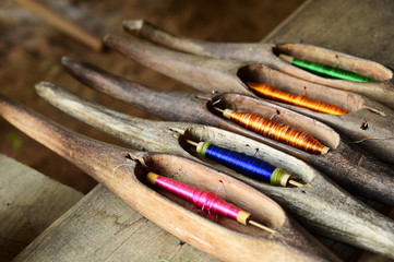 Close up of spool with colorful thread in wooden local equipment for weaving fabric in traditional Thai style