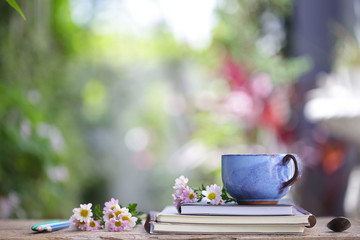 Old blue cup and notebook with flower on wooden table