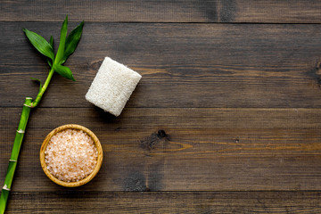 Asian spa procedure with natural ingredients concept. Bamboo branch, spa cosmetics on dark wooden background top view copy space