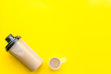 sport nutrition set with protein powder for cocktail and scoop on yellow background top view space for text