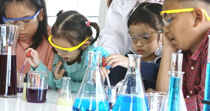 Science teacher teach Asian students in laboratory room,  Student drop something into colorful tube, colorful test tube and microscope on table , concept for study in laboratory room.