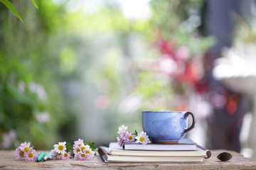 Old blue cup and notebook with flower on wooden table