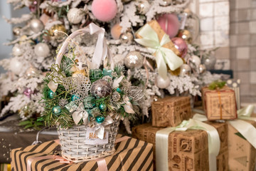 Christmas or New Year background: basket with colored glass toys and balls, decoration and gifts on wooden background near christmas tree.Happy holidays.