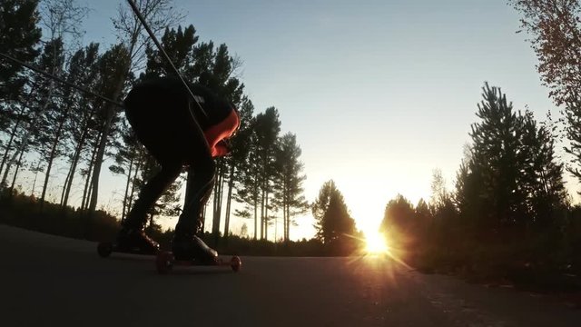 Training an athlete on the roller skaters. Biathlon ride on the roller skis with ski poles, in the helmet. Autumn workout. Roller sport. Adult man riding on skates. Shooting action cam. Slow motion.