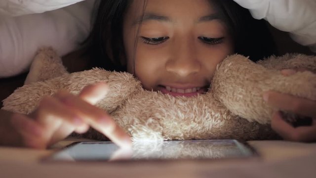 Little girl using tablet in the bedroom.
