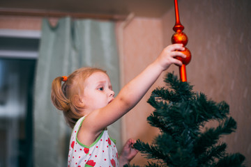 little baby decorates the Christmas tree