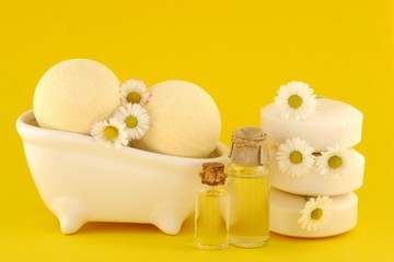 Chamomile essential oil, soap and bath bombs with chamomile extract on a  yellow background.set of cosmetics for the body with chamomile extract
