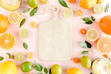 Сutting board frame and summer tropical fruits: orange, lemon, lime, mango on pink background. Food concept. flat lay, top view