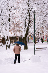 middle aged man walking in the snow with an umbrella