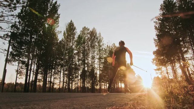 Training an athlete on the roller skaters. Biathlon ride on the roller skis with ski poles, in the helmet. Autumn workout. Roller sport. Adult man riding on skates. The run goes very close to the