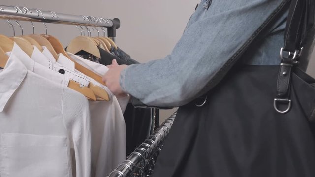 A woman in a store chooses clothes and steals her discreetly, putting them in a bag