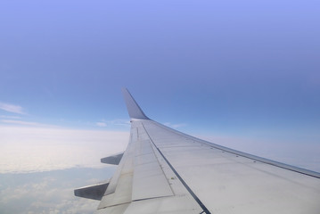 wing of airplane over the sky with clouds and sunlight 