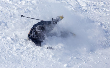 A man fell on skis from a mountain in the snow