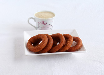 Kodubale, which is a delicious, bracelet-shaped vegetarian snack and a food native to Karnataka, India, on a tray, and filter coffee.