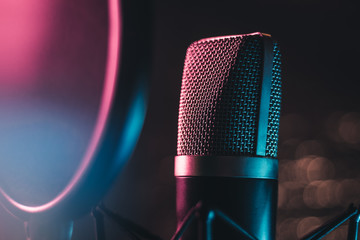 Colourful mic in studio setting - Close up macro shot of microphone in studio glowing with colorful...