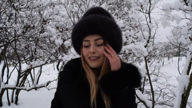 Portrait of a beautiful girl in a hat in the winter forest on the background of snow branches.
