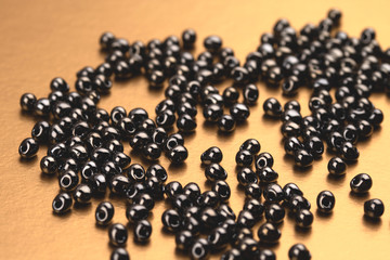 Bunch of black beads on golden surface.