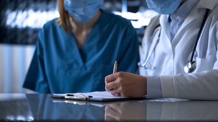 Female and male interns filling registration form and discussing patient illness
