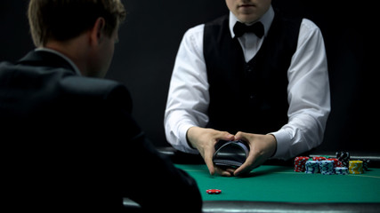 Experienced casino croupier making shuffling tricks with cards, chance to win