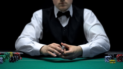Professional croupier holding cards, ready for poker game in casino, gambling