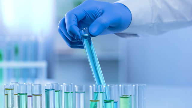 Assistant checking blue substance in test tube, laundry detergent production
