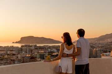 Young couple watching sunset from the rooftop terrace - obrazy, fototapety, plakaty