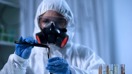 Laboratory assistant pouring petrochemical into test tube, petroleum industry