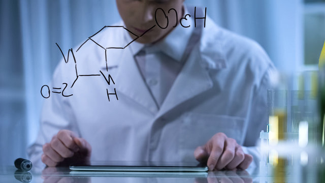 Chemist finishing formula on glass board, entering research result in tablet