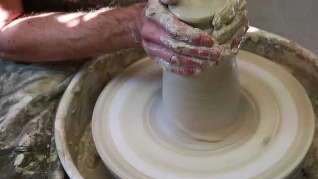      Artist potter in the workshop creating a ceramic vase. Hands closeup. Twisted potter's wheel. Small artistic craftsmen business concept. 