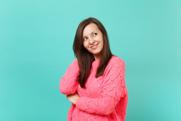 Stunning beautiful young woman in knitted pink sweater looking aside up isolated on blue turquoise wall background, studio portrait. People sincere emotions, lifestyle concept. Mock up copy space.