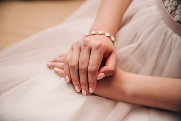 hands with a manicure lie on a wedding dress