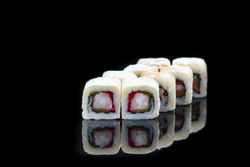 Sushi rolls with salmon, tuna, cucumber and green onions on black background