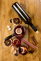 Mulled wine with ingredients on wooden background, top view.